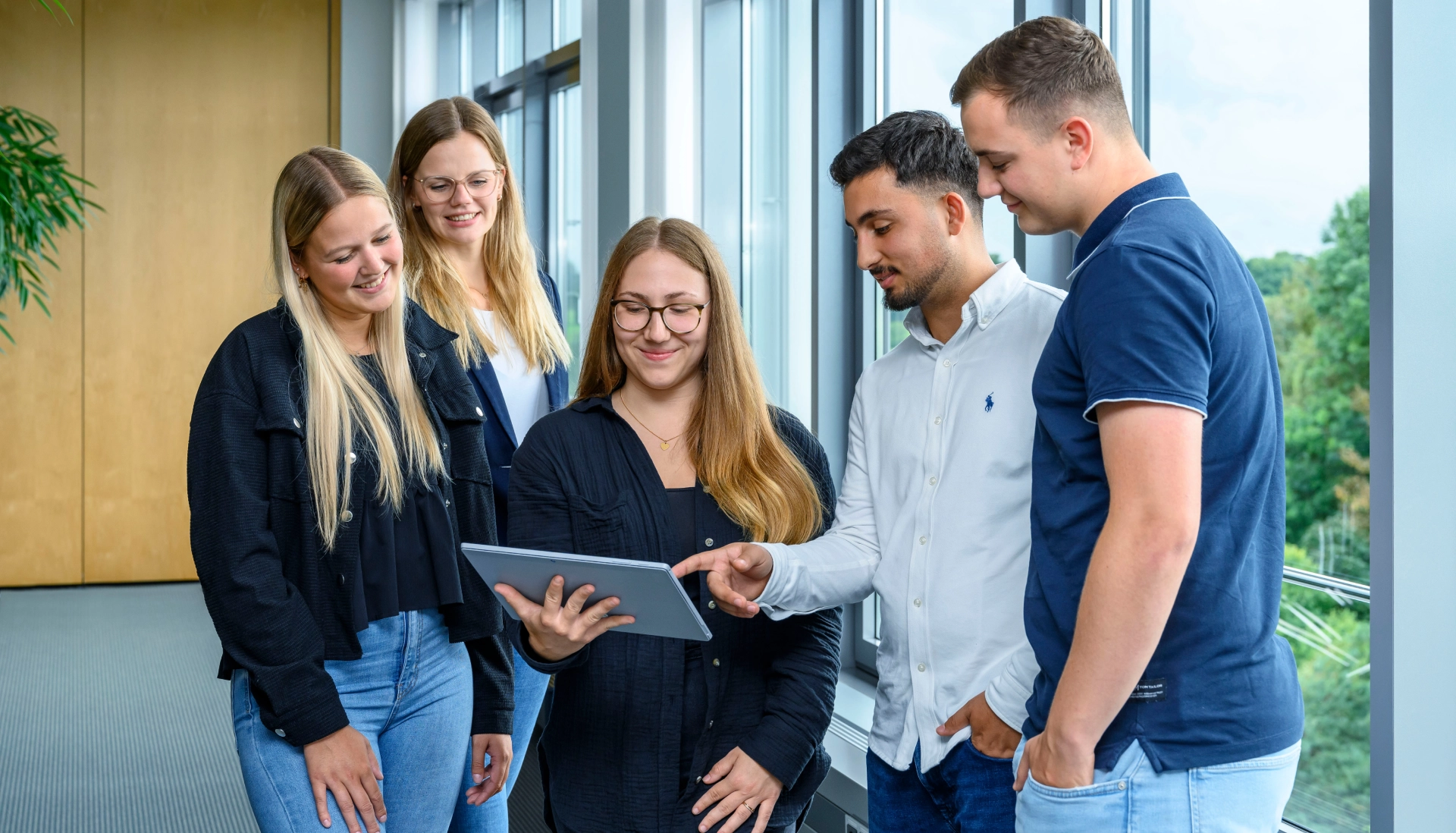 5 Angestellte im Konferenzraum vor einem Tablet