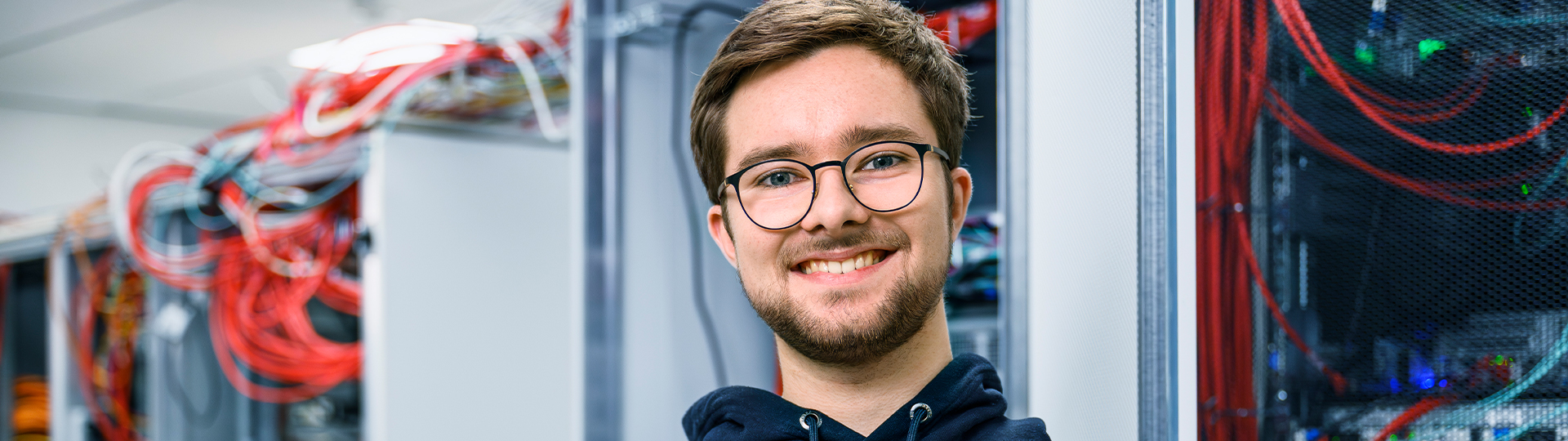 Junger Mitarbeiter der IT im Serverraum