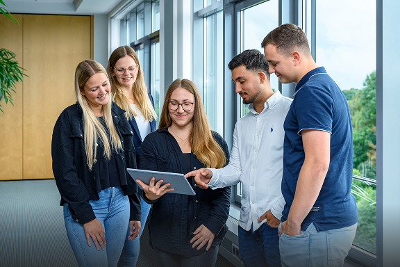 Mehrere Studierende schauen gemeinsam auf ein Tablet.